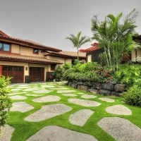 A beautifully landscaped home with a stone pathway, surrounded by tropical plants and greenery.